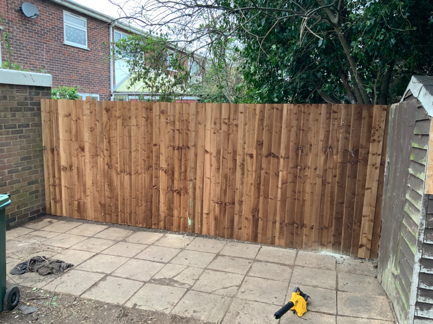 Finished close-board timber fence replacing an overgrown boundary