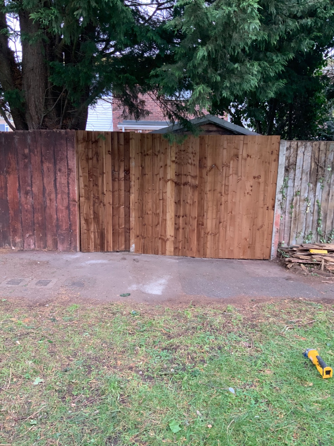 Mid-installation showing new fence panels alongside old fencing
